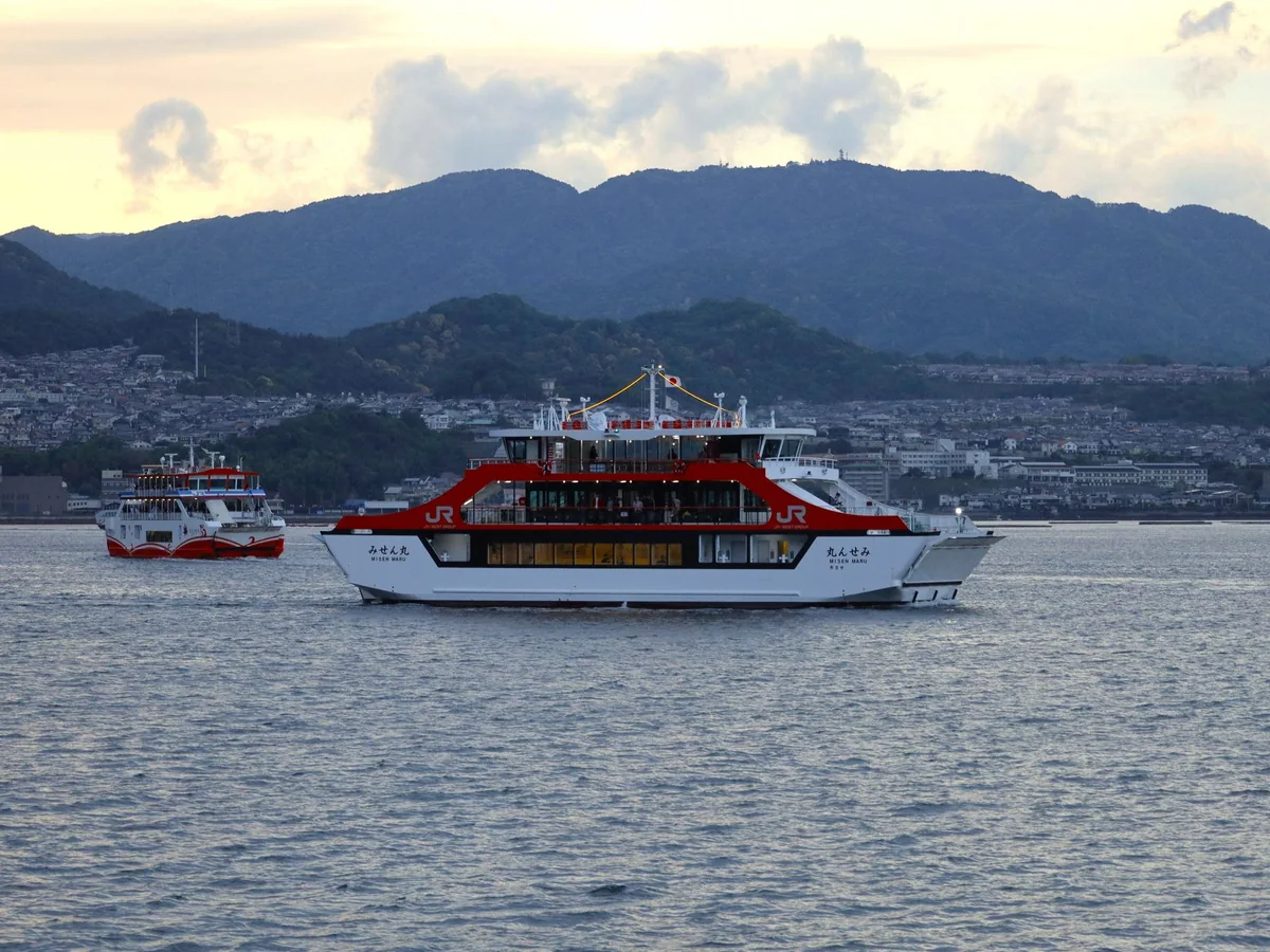 A JR ferry crossing the Seto Inland Sea toward Miyajima with mountains behind it